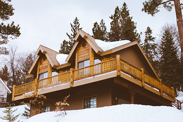 На фото дом в зимнем лесу
